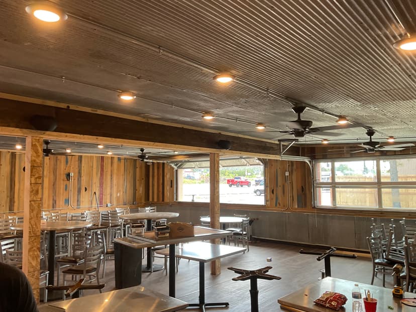 Interior of a rustic restaurant with wooden walls, metal ceiling, and empty dining area.